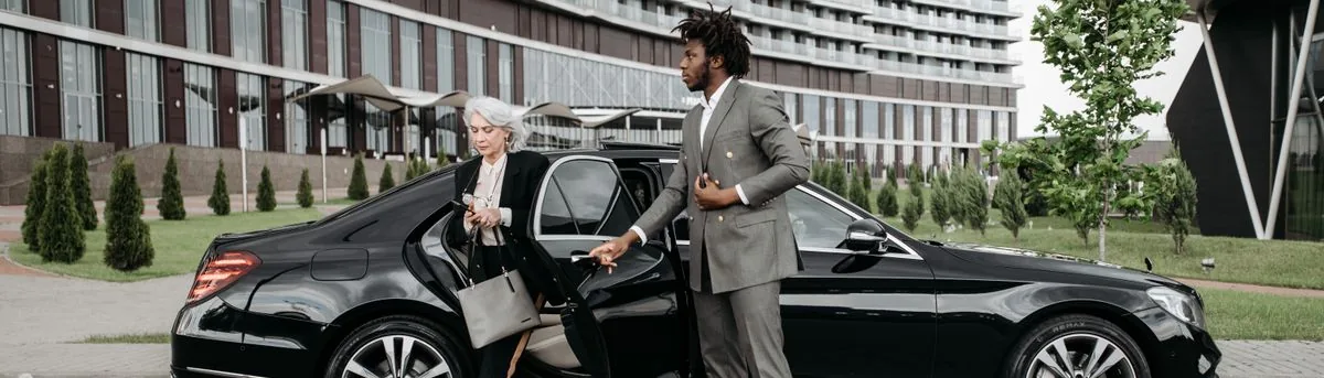 Chauffeur aidant une passagère à descendre de voiture