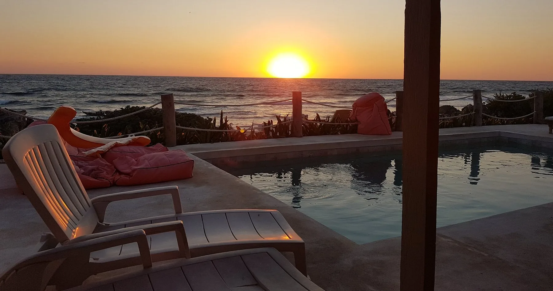 Le soleil sur la mer près de la piscine et des poufs à Punta Piedra Studios
